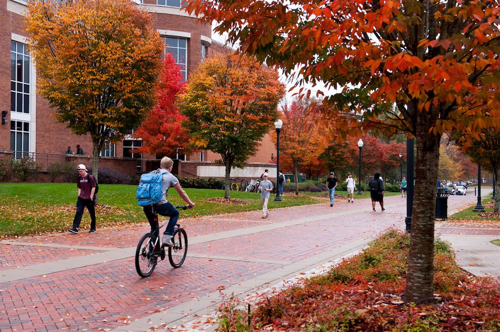 Student riding bike down brick sidewalk